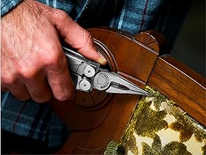 Photo of person pulling a staple out of upholstery attached to a chair with the Wave+ multi-tool