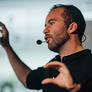 A man in a black shirt presenting at a conference.